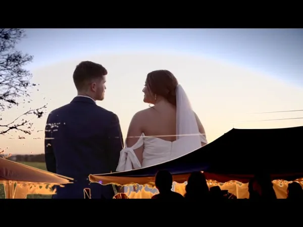 A bride and groom standing together at an outdoor wedding reception during sunset.