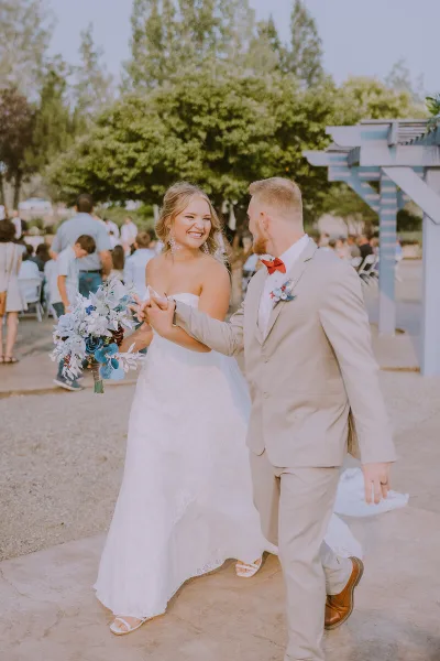 A bride and groom dancing at an outdoor wedding reception with guests seated in the background.