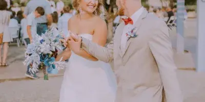 A bride and groom dancing at an outdoor wedding reception with guests seated in the background.