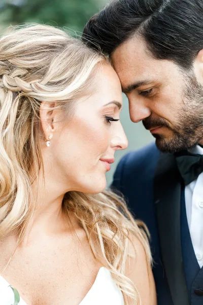 A close-up profile portrait of a bride and groom touching foreheads.