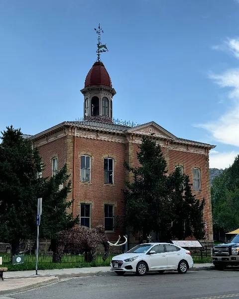 Exterior view of the Historic Chaffee County Courthouse, a red brick building with a distinctive dome and deer weathervane.