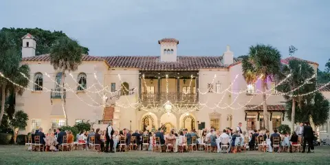 Outdoor wedding reception at a Spanish-style venue with string lights and seated guests.
