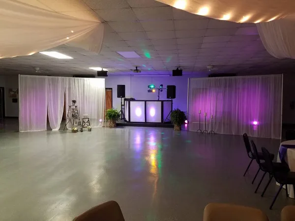 A dance floor setup featuring a professional DJ booth with illuminated panels, speakers, and colorful stage lighting.