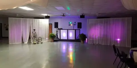 A dance floor setup featuring a professional DJ booth with illuminated panels, speakers, and colorful stage lighting.