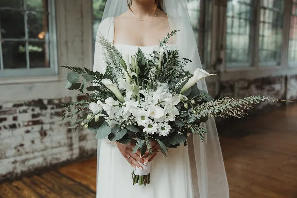 Bride holding a white and green bridal bouquet with calla lilies and eucalyptus