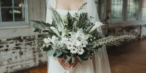 Bride holding a white and green bridal bouquet with calla lilies and eucalyptus