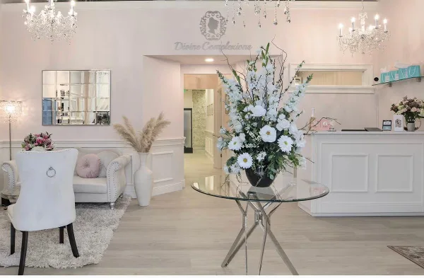 Divine Complexions spa lobby with white reception desk, seating area, floral arrangement, and chandeliers