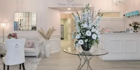 Divine Complexions spa lobby with white reception desk, seating area, floral arrangement, and chandeliers