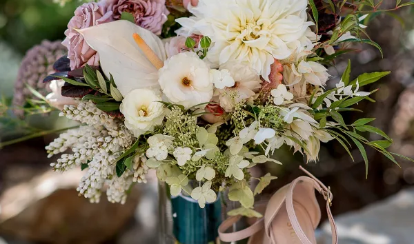Close-up of a wedding floral arrangement with white calla lilies, pink roses, and greenery.