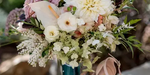 Close-up of a wedding floral arrangement with white calla lilies, pink roses, and greenery.