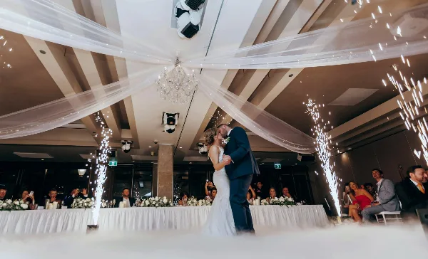 A bride and groom dancing at a wedding reception with sparklers and professional lighting.