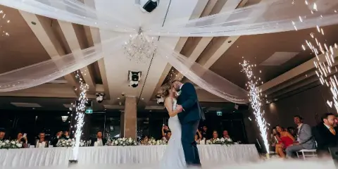 A bride and groom dancing at a wedding reception with sparklers and professional lighting.