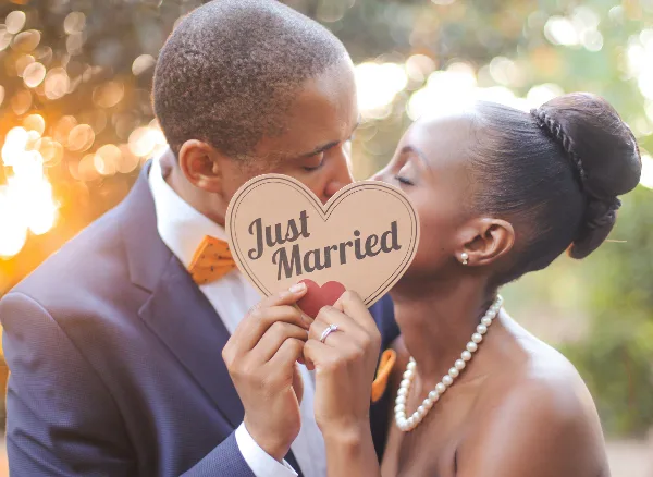 A bride and groom holding a 'Just Married' sign outdoors.