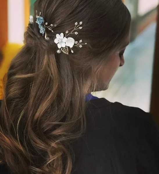 Close-up of a woman's styled hair featuring a half-up, half-down look with floral hair accessories.