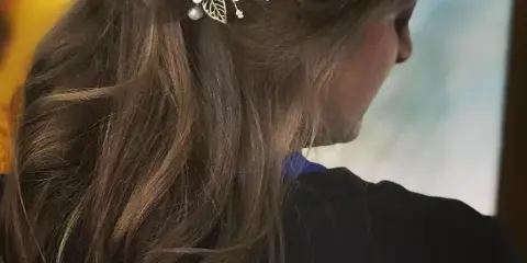 Close-up of a woman's styled hair featuring a half-up, half-down look with floral hair accessories.
