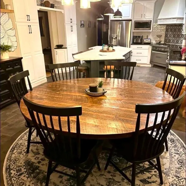 A rustic wooden dining table surrounded by dark wooden chairs in a modern kitchen setting.