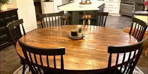 A rustic wooden dining table surrounded by dark wooden chairs in a modern kitchen setting.