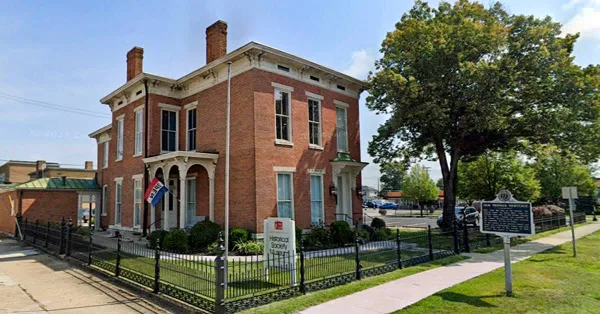 Exterior view of the Bartholomew County Historical Society museum building, a two-story red brick structure with a white sign in the front yard.