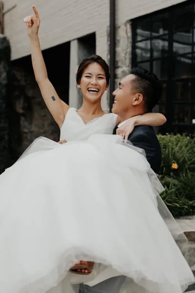 A bride and groom laughing and celebrating outdoors in front of a historic building.
