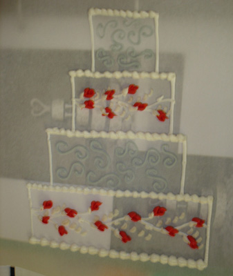 Decorated tiered wedding cake with red flower accents