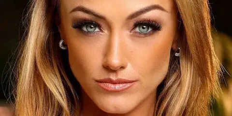 Close-up portrait of a woman with professionally applied makeup and styled blonde hair.
