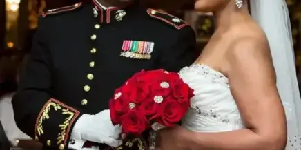 A bride and groom in formal wedding attire standing together in a ballroom.