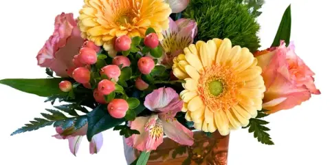 A floral arrangement featuring yellow gerbera daisies, pink alstroemeria, and pink berries in an amber glass vase.