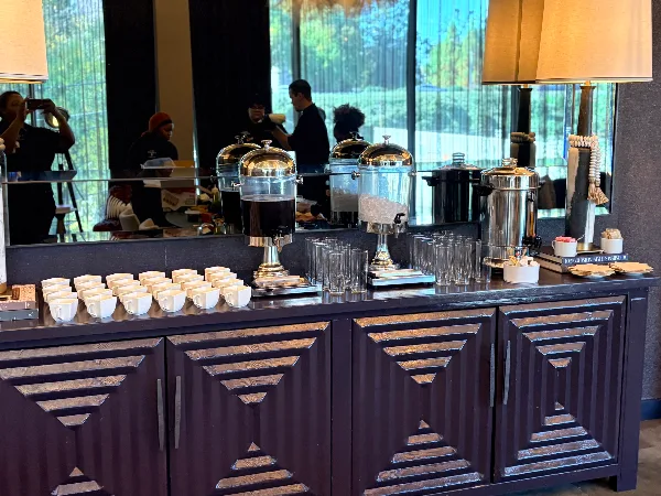 Catering service station with beverage dispensers, glassware, and staff in an event venue