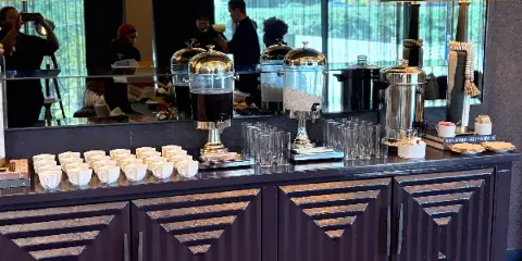 Catering service station with beverage dispensers, glassware, and staff in an event venue