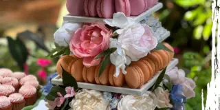 A multi-tiered wedding dessert tower decorated with macarons and fresh flowers.