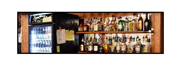 Interior bar area with shelves of liquor bottles and a glass-door beverage cooler