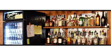 Interior bar area with shelves of liquor bottles and a glass-door beverage cooler