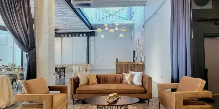 A vintage-style lounge set with a brown sofa, two armchairs, and a patterned rug arranged in a studio space.