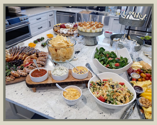 A buffet table filled with assorted salads, pastries, bread, and desserts in a bright kitchen