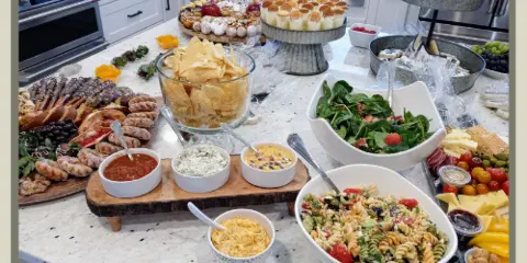 A buffet table filled with assorted salads, pastries, bread, and desserts in a bright kitchen