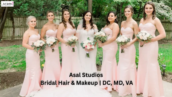 A bride and six bridesmaids in pink dresses standing outdoors, showcasing professional bridal hair and makeup.