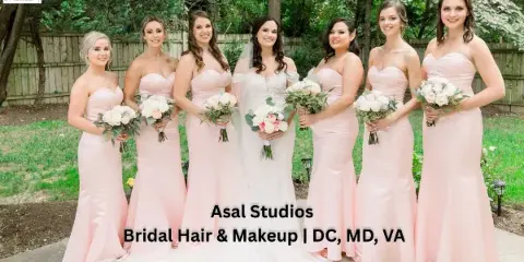 A bride and six bridesmaids in pink dresses standing outdoors, showcasing professional bridal hair and makeup.