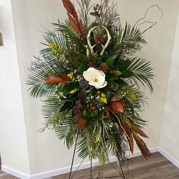 Tall floral standing spray with white bloom and mixed greenery on an easel