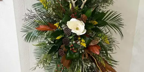 Tall floral standing spray with white bloom and mixed greenery on an easel
