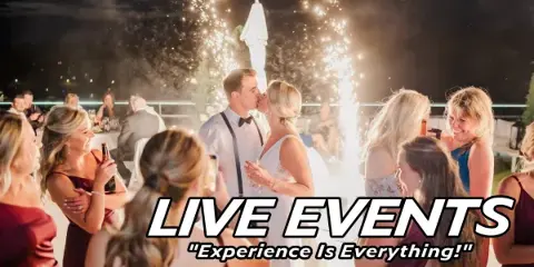 A wedding couple kissing during a reception with cold sparklers and guests watching.