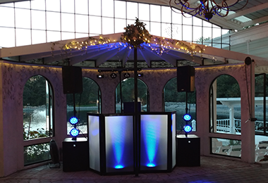 Professional DJ booth with illuminated panels, speakers, and event lighting set up in a venue.