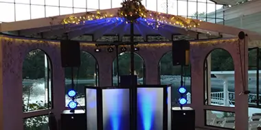 Professional DJ booth with illuminated panels, speakers, and event lighting set up in a venue.