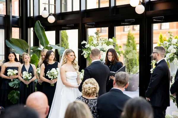 A wedding officiant performing a ceremony for a bride and groom in a modern venue.