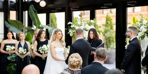 A wedding officiant performing a ceremony for a bride and groom in a modern venue.