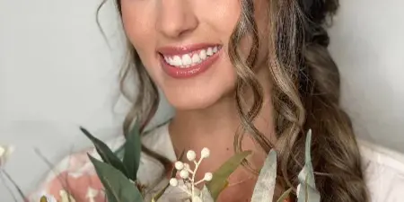 Bride with styled braided hair and makeup holding a floral bouquet