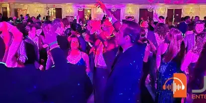 Guests dancing at a wedding reception under purple and blue lighting