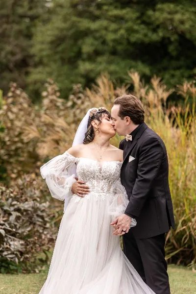 A bride and groom sharing a kiss in an outdoor garden setting.