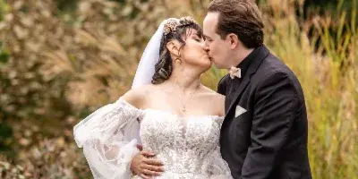 A bride and groom sharing a kiss in an outdoor garden setting.