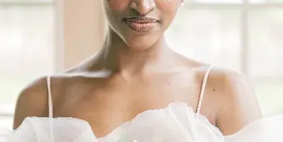 Portrait of a bride in a white gown holding a bouquet of white roses.