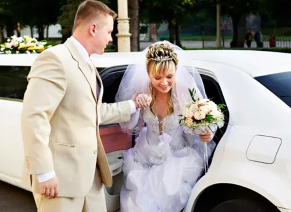 Bride and groom exiting a white limousine during a wedding